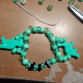 green bracelet with dinosaur charms and censored letter 
      beads