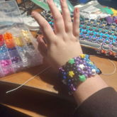 kandi cuff with stars as anchor beads and purple blue and 
    black main beads visible